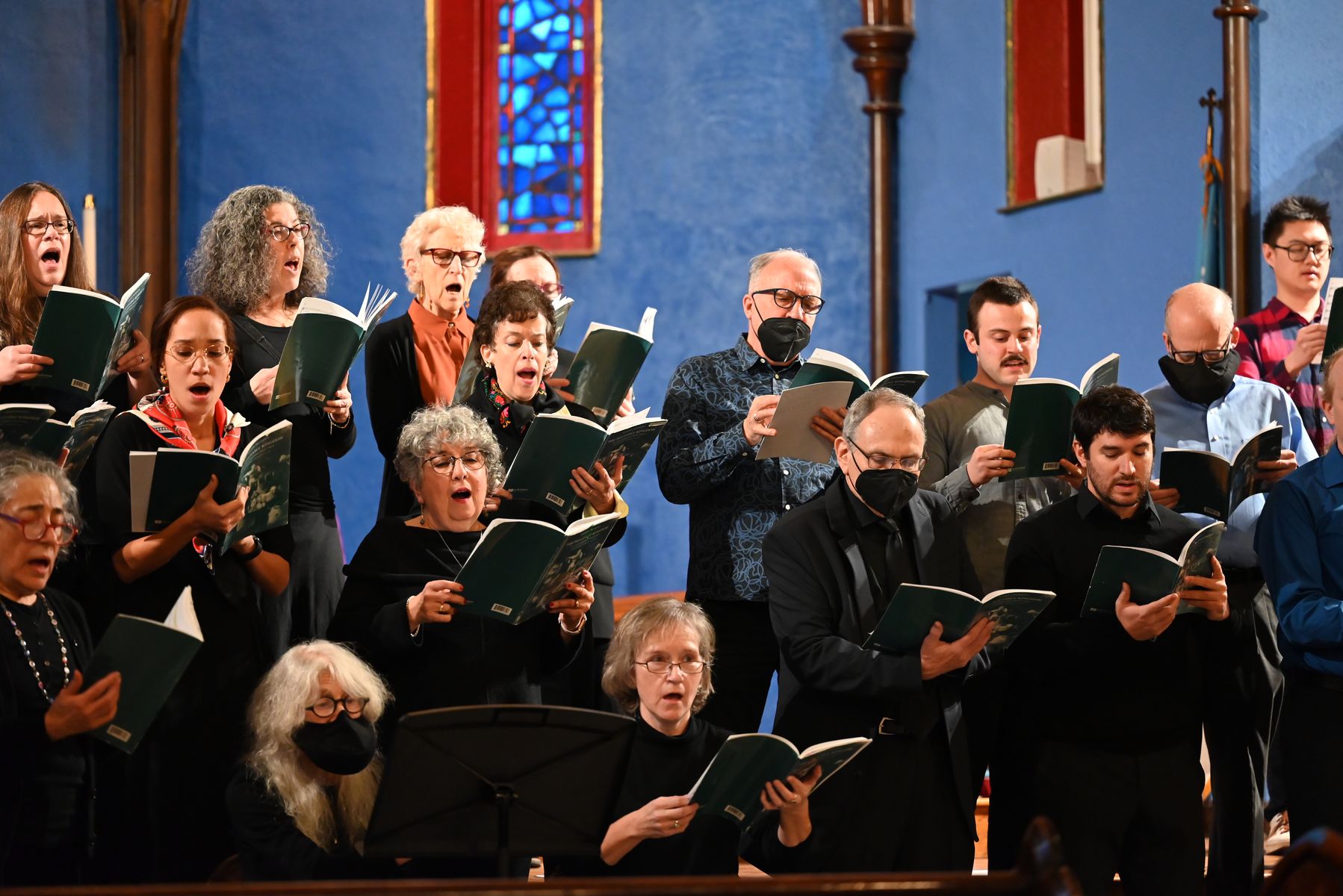 Singers mid-phrase in concert, holding their scores