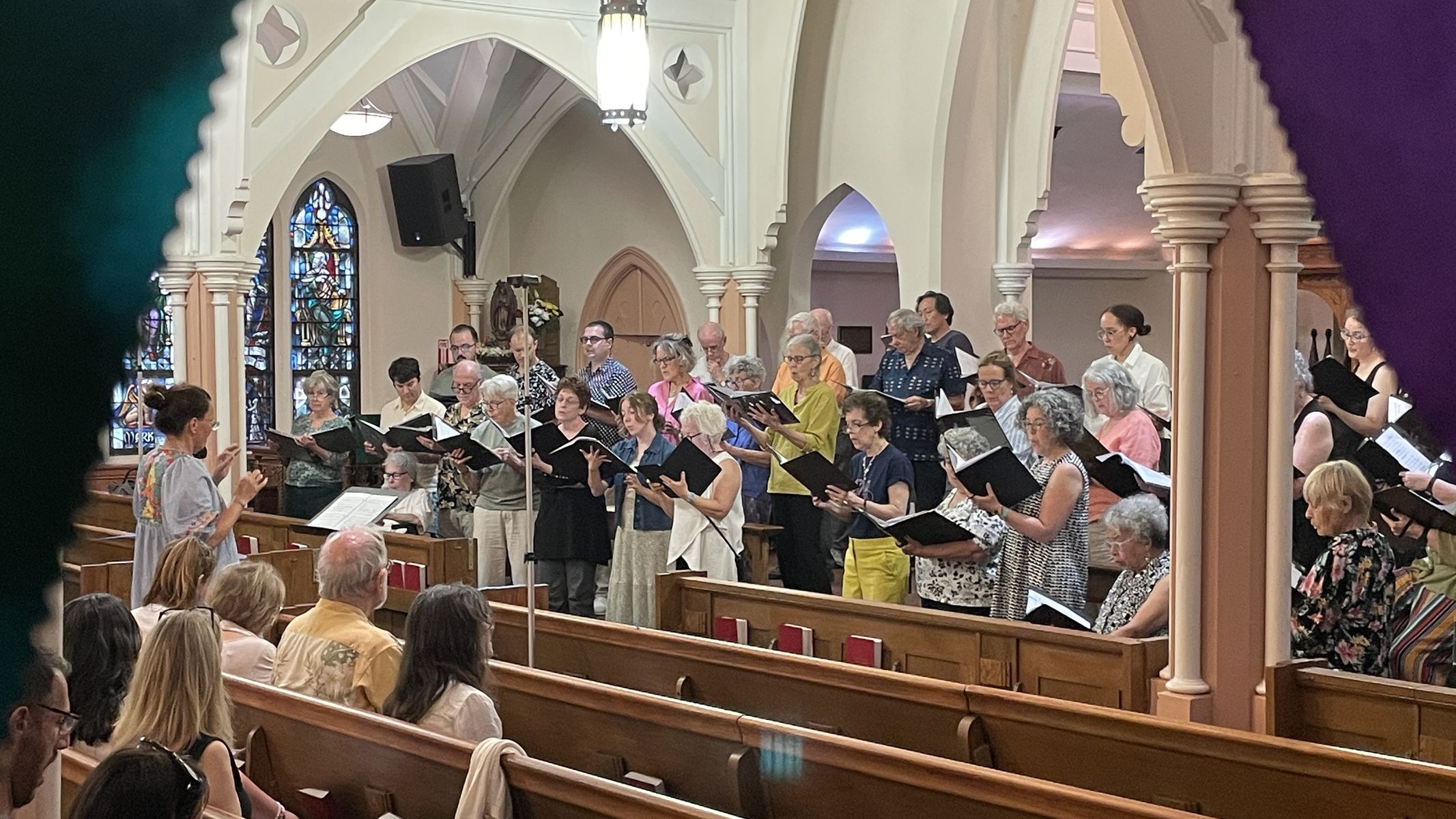 The choir singing beneath church arches as the audience listens from the pews
